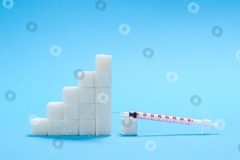 Скачать Концепция сахарной зависимости и развития сахарного диабета. Кубики сахара и шприц на синем медицинском фоне. фотосток Ozero