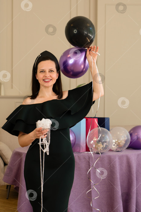 Скачать Женщина с воздушными шарами и украшениями в руках улыбается на вечеринке по случаю дня рождения. фотосток Ozero