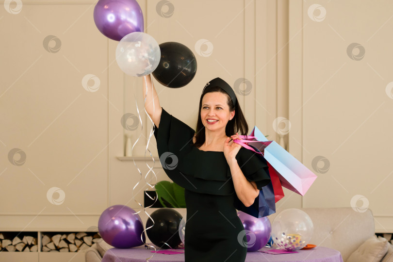 Скачать Женщина в черном платье держит воздушные шары и позирует на вечеринке фотосток Ozero