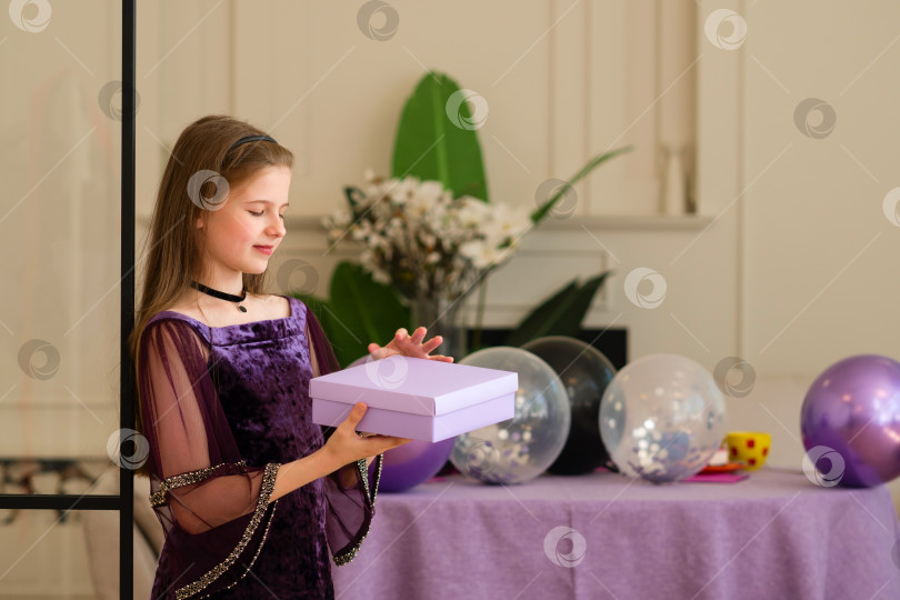 Скачать Девушка в фиолетовом платье держит подарочную коробку на вечеринке по случаю дня рождения фотосток Ozero