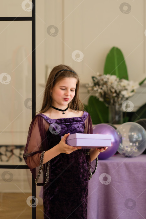 Скачать Девушка смотрит на подарочную коробку на вечеринке по случаю дня рождения. фотосток Ozero