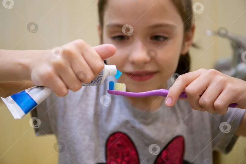Скачать Маленькая девочка выдавливает зубную пасту на щетку. Понятие о здоровье детей, медицине, профилактике. фотосток Ozero