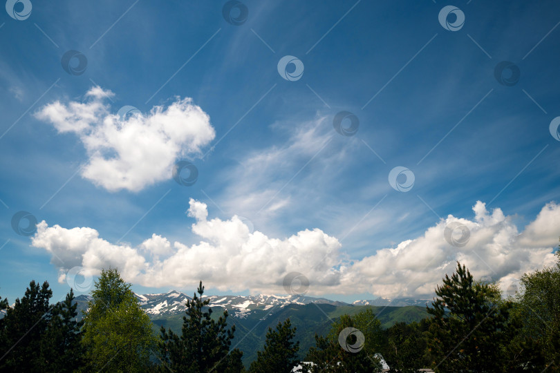 Скачать Заснеженные горы под голубым небом с облаками. фотосток Ozero