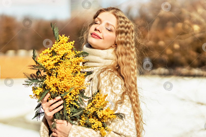 Скачать Портрет молодой женщины со светлыми волосами, держащей в руках букет мимозы. Весна фотосток Ozero