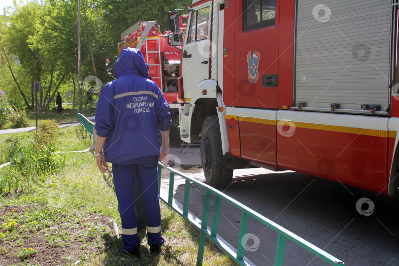 Скачать Сотрудник скорой помощи около пожарной машины во время тушения пожара фотосток Ozero