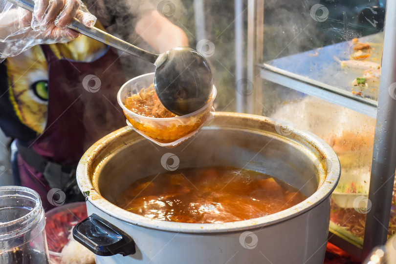 Скачать Вьетнамская женщина подает суп с лапшой и мясом на вьетнамском ночном рынке во время фестиваля еды фотосток Ozero