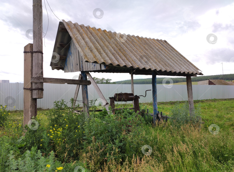 Скачать Старый колодец, заросший травой у забора фотосток Ozero