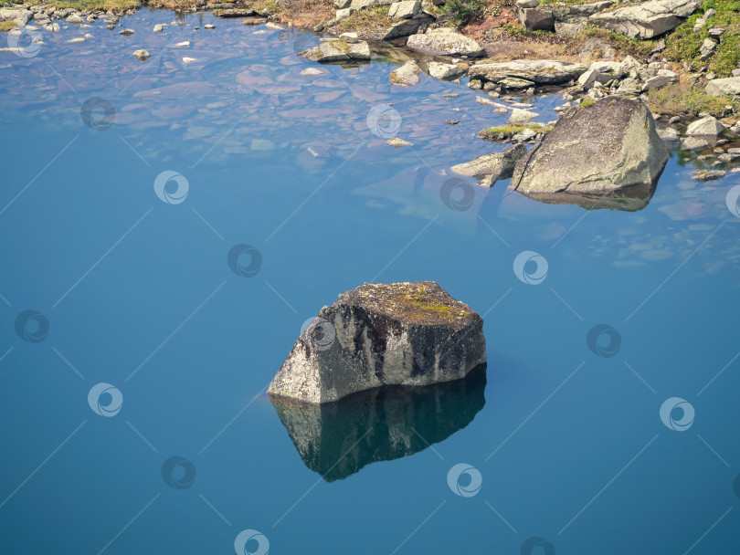 Скачать Отражение камня в неподвижной прозрачной голубой воде. фотосток Ozero