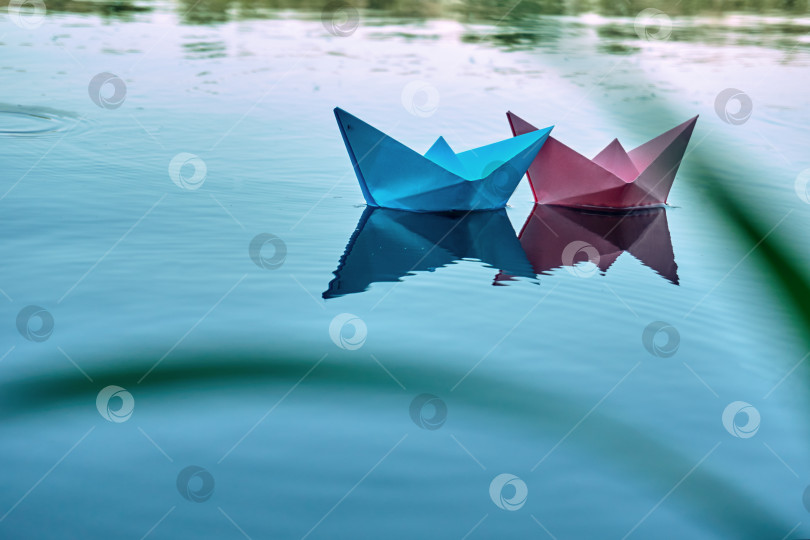 Скачать Две лодки голубого и розового цветов плывут по реке. Летний день, отдых на пруду фотосток Ozero
