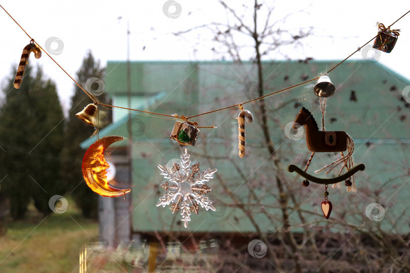 Скачать фотография рождественской декоративной гирлянды с игрушками на окне в деревне фотосток Ozero