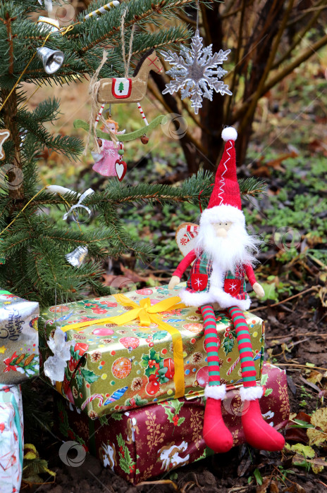 Скачать Рождественский гном сидит на коробках с подарками возле рождественской елки фотосток Ozero