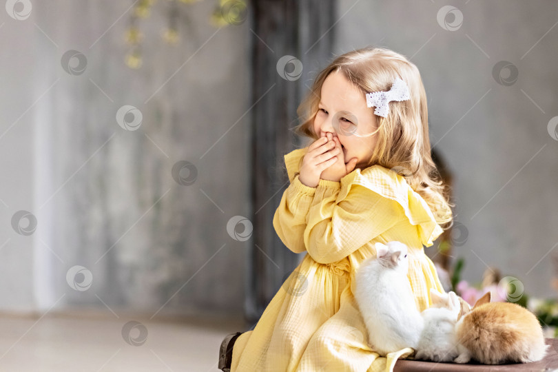 Скачать Маленькая светловолосая малышка в желтом платье сидит на старых чемоданах с живыми кроликами. Эмоции. Светлый праздник Пасхи.Китайский год кролика фотосток Ozero