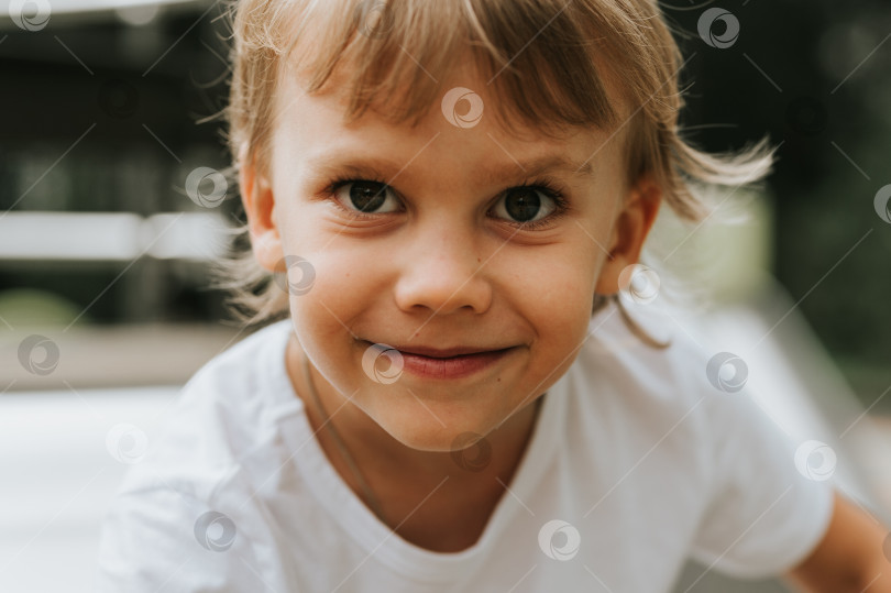 Скачать портретное лицо милого маленького счастливого улыбающегося искреннего пятилетнего мальчика с большими глазами и длинными светлыми волосами в белой футболке. поколение z дети психическое здоровье образ жизни и психология разума фотосток Ozero