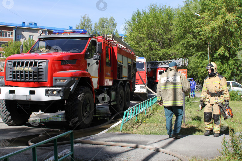 Скачать Сотрудники МЧС России около пожарных машин во время тушения пожара фотосток Ozero