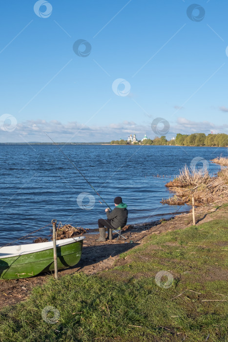 Скачать Вид сзади на мужчину, который в одиночестве ловит рыбу на озере. фотосток Ozero