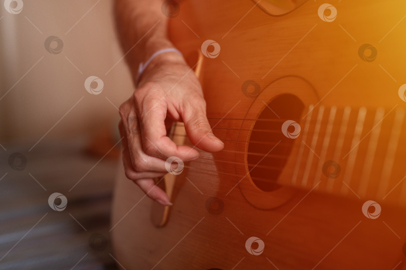 Скачать мужские руки пожилого кавказца старшего возраста, держащего классическую гитару и играющего на ней крупным планом дома. непрофессиональные безликие гитаристы играют любительскую музыку. домашние хобби и досуг фотосток Ozero