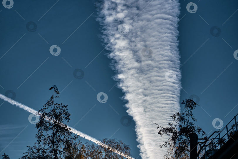 Скачать Широкий густой след выхлопа от летящих самотлетов в синем-синем небе. Загрязнение окружающей среды фотосток Ozero