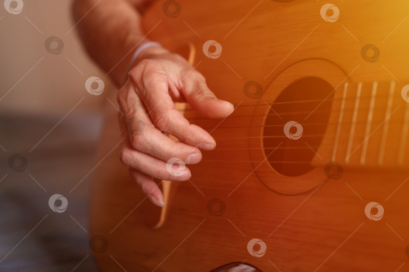 Скачать мужские руки пожилого кавказца старшего возраста, держащего классическую гитару и играющего на ней крупным планом дома. непрофессиональные безликие гитаристы играют любительскую музыку. домашние хобби и досуг фотосток Ozero