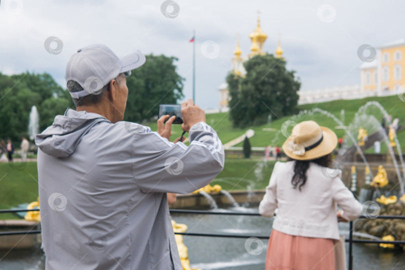 Скачать туристы фотографируются на фоне Большого каскада в дворцовом парке Петергоф, Санкт-Петербург фотосток Ozero