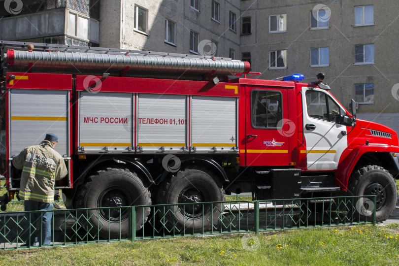 Скачать Сотрудник МЧС России пожарного расчета около пожарной машины во время тушения пожара фотосток Ozero