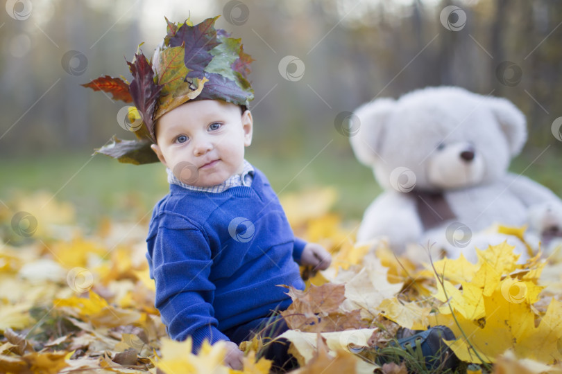 Скачать Счастливый ребенок в осеннем парке играет с листьями. фотосток Ozero