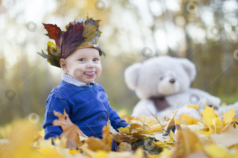 Скачать Счастливый ребенок в осеннем парке играет с листьями. фотосток Ozero
