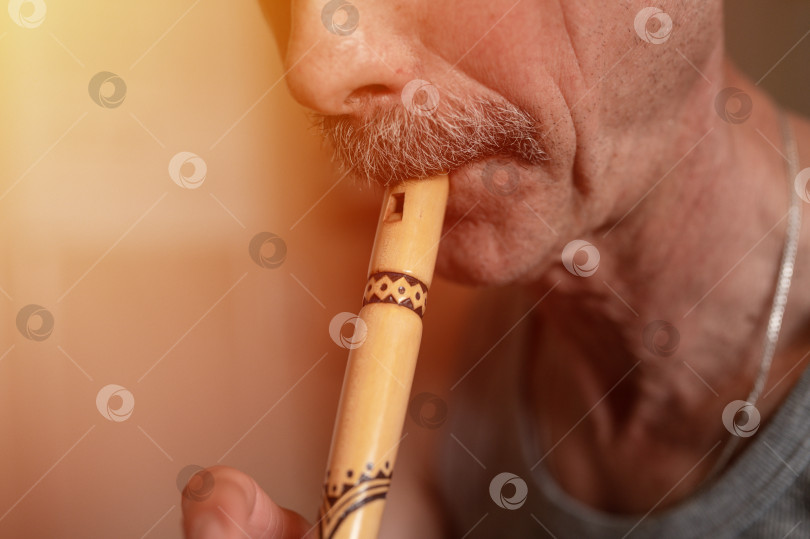 Скачать пожилой мужчина, играющий на флейте. безликий непрофессиональный мужчина пожилого кавказского происхождения с усами, ртом и губами играет на трубе любительскую музыку крупным планом дома. хобби и досуг фотосток Ozero