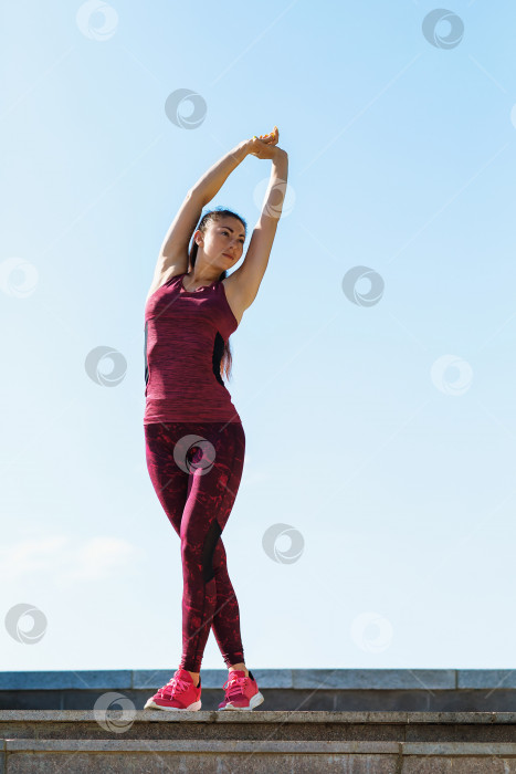Скачать Молодая женщина выполняет зарядку солнечным летним утром на открытом воздухе фотосток Ozero