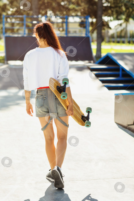 Скачать Солнечным утром девушка отправляется кататься на лонгборде в скейт-парк фотосток Ozero