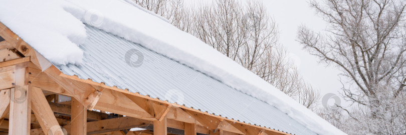 Скачать снег, сползающий с крыши. строительный дом с металлической крышей, покрытый свежим ледяным замерзшим снегом и снежинками в морозный зимний день в пригороде деревни. снежный зимний сезон. холодная погода фотосток Ozero