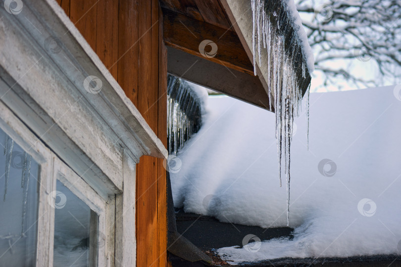 Скачать Ледяные сосульки тают на крыше загородного дома. фотосток Ozero