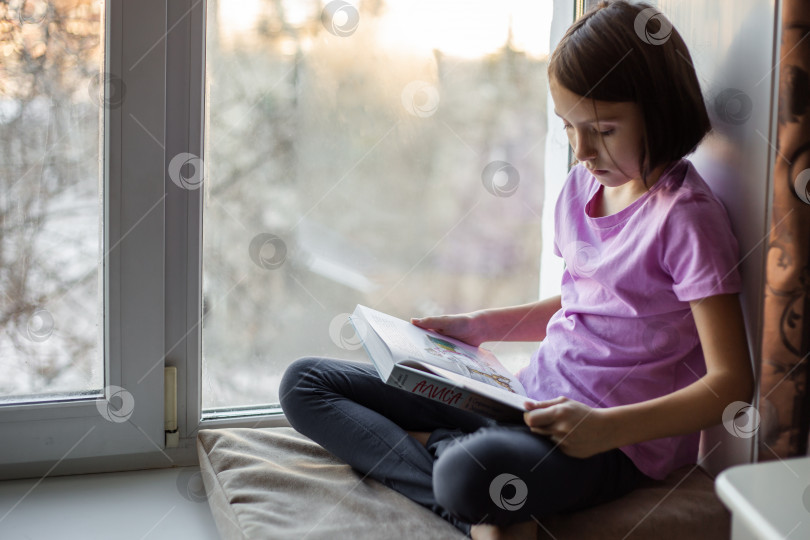 Скачать Девочка-подросток читает книгу на подоконнике фотосток Ozero