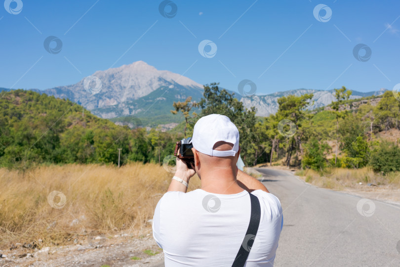 Скачать Мужчина фотографирует горы в солнечный день. фотосток Ozero