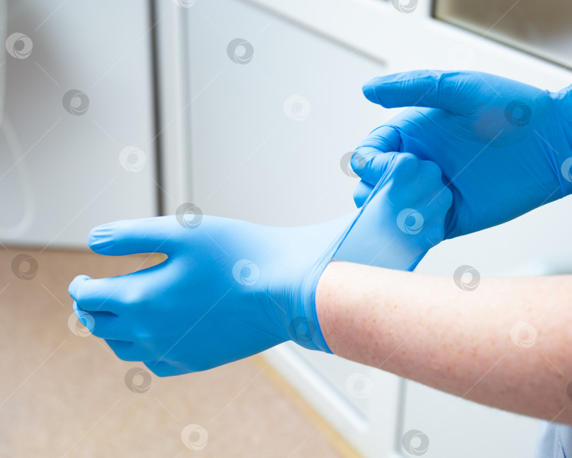 Скачать Руки надевают медицинские синие перчатки фотосток Ozero