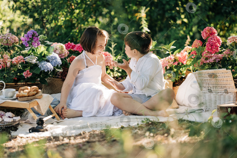 Скачать Счастливые дети, мальчик и девочка, романтическая фотография на пикнике в парке с летними цветами. Мальчик и девочка фотосток Ozero