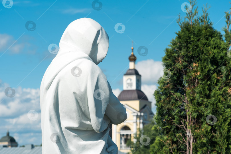 Скачать исторический городской пейзаж, скульптура в плаще с капюшоном на фоне старинной колокольни с часами фотосток Ozero