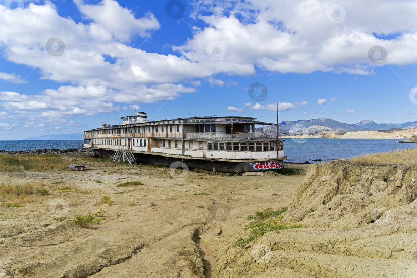 Скачать На берегу моря стоит старая заброшенная речная лодка. фотосток Ozero