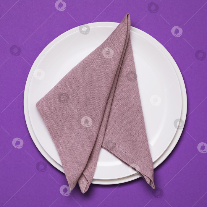 Скачать Свернутая салфетка в тарелке на фиолетовом фоне, вид сверху фотосток Ozero