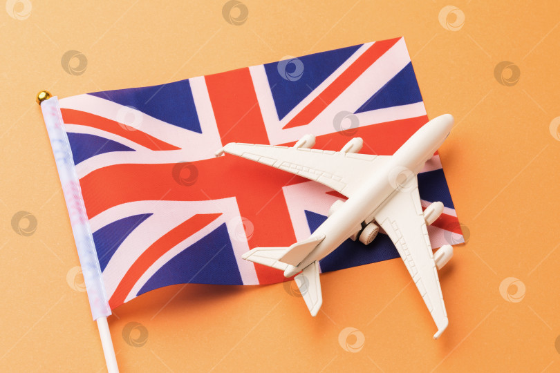 Скачать Флаг Великобритании и игрушечный самолет на оранжевом фоне, концепция полета в Соединенное Королевство фотосток Ozero