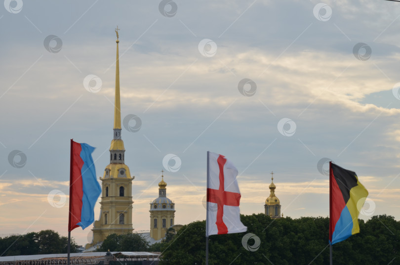 Скачать Санкт-Петербург, Россия – 07.27.2024: Петропавловская крепость на Заячьем острове в Санкт-Петербурге на фоне флагов украшающих Троицкий мост ко дню Военно-морского флота фотосток Ozero