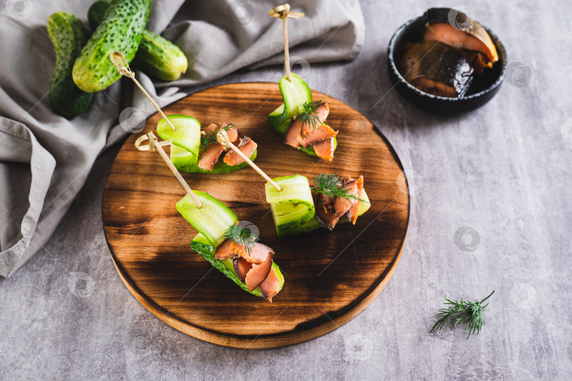 Скачать Вкусные канапе из огурцов, красной рыбы и укропа на доске на стол фотосток Ozero