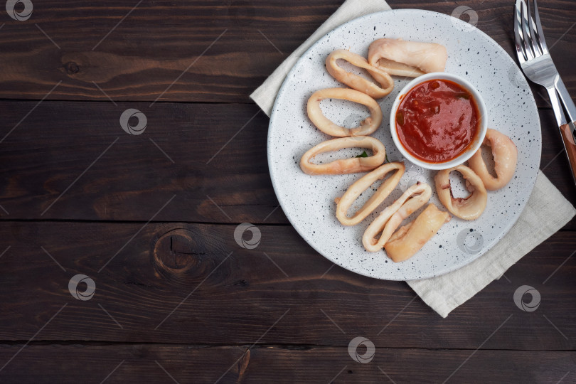 Скачать Обжаренные кольца кальмара с томатным соусом и лимоном. Пространство для копирования фона из темного дерева. Вид сверху. фотосток Ozero