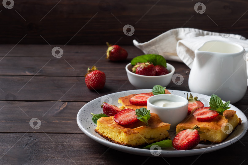 Скачать Творожная запеканка с клубникой и мятой. Вкусный домашний десерт из творога и свежих ягод со сливками. фон из темного дерева, копия пространства. фотосток Ozero