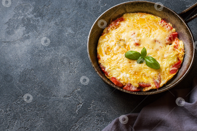 Скачать Омлет-болтунья с помидорами и сыром на сковороде на темном столе. фотосток Ozero