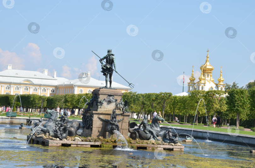 Скачать Санкт-Петербург, Россия – 07.27.2024: Верхний сад Государственного музея-заповедника Петергоф в Санкт-Петербурге: фонтан Нептун, вид на Большой петергофский дворец и Церковь Петра и Павла в ясный летний день фотосток Ozero