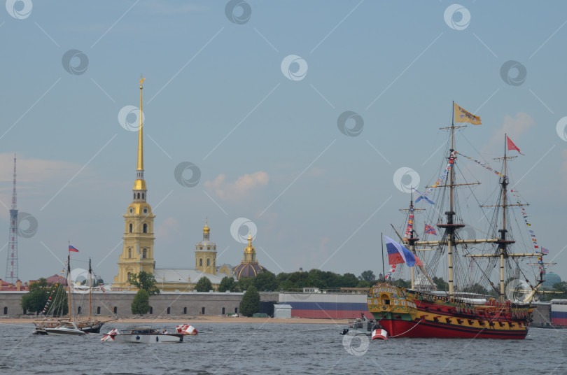 Скачать Санкт-Петербург, Россия – 07.27.2024: Корабль «Полтава» (реконструкция первого парусного линейного корабля Российской империи, спущенного на воду в 1712 году) на фоне Петропавловской крепости в Санкт-Петербурге перед парадом на День ВМФ фотосток Ozero