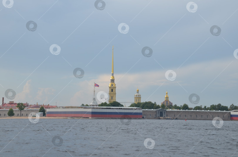 Скачать Санкт-Петербург, Россия – 07.27.2024: Петропавловская крепость на Заячьем острове в Санкт-Петербурге на фоне флагов украшающих Троицкий мост ко дню Военно-морского флота фотосток Ozero