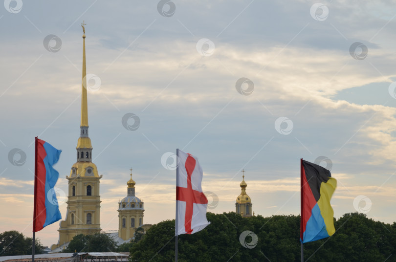 Скачать Санкт-Петербург, Россия – 07.27.2024: Петропавловская крепость на Заячьем острове в Санкт-Петербурге на фоне флагов украшающих Троицкий мост ко дню Военно-морского флота фотосток Ozero