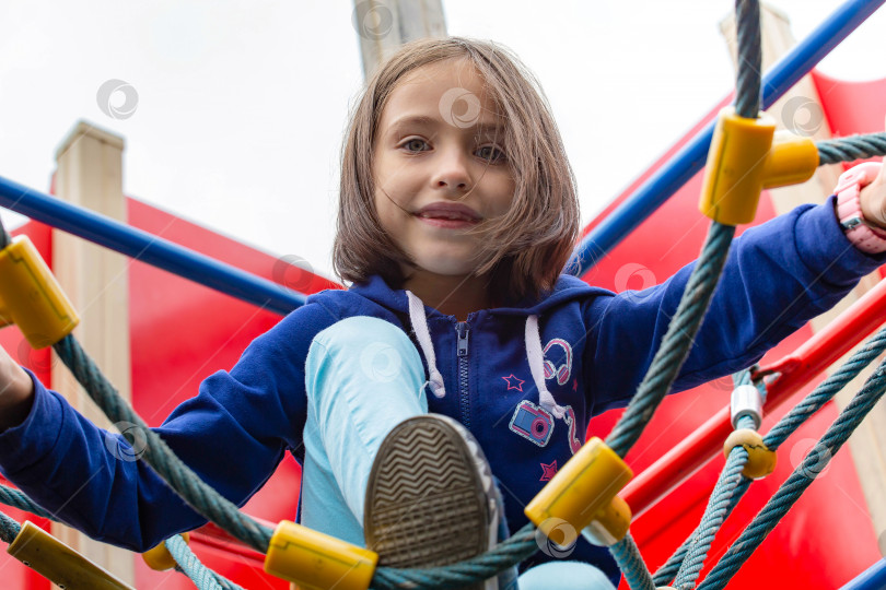 Скачать Активная маленькая девочка на детской площадке. Вид снизу вверх. фотосток Ozero