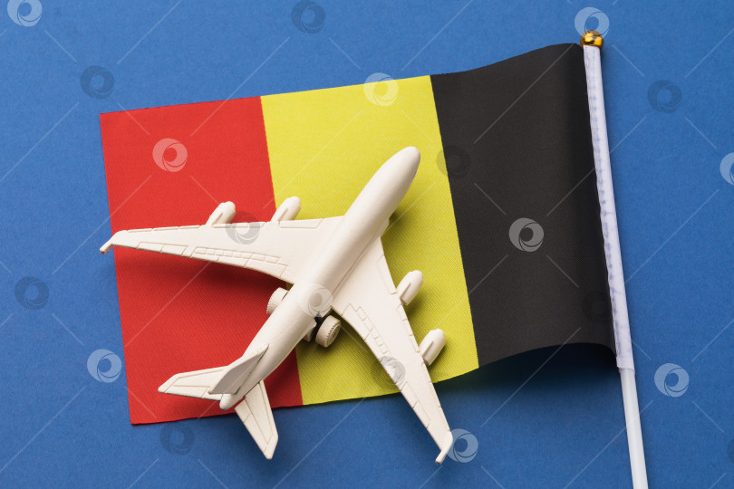 Скачать Флаг Бельгии и игрушечный самолетик на синем фоне, концепция на тему путешествия в Бельгию, вид сверху фотосток Ozero